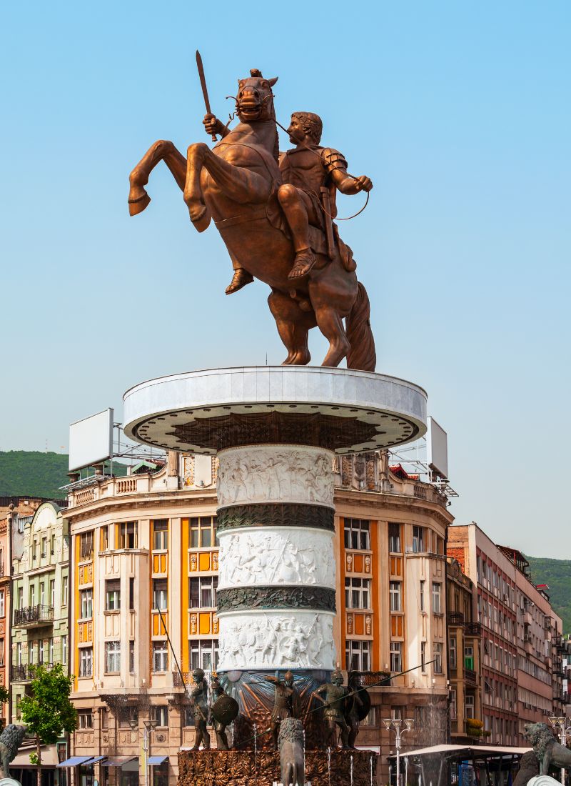 An image of the Alexander the Great statue in the main square of skopje with mountains in the background