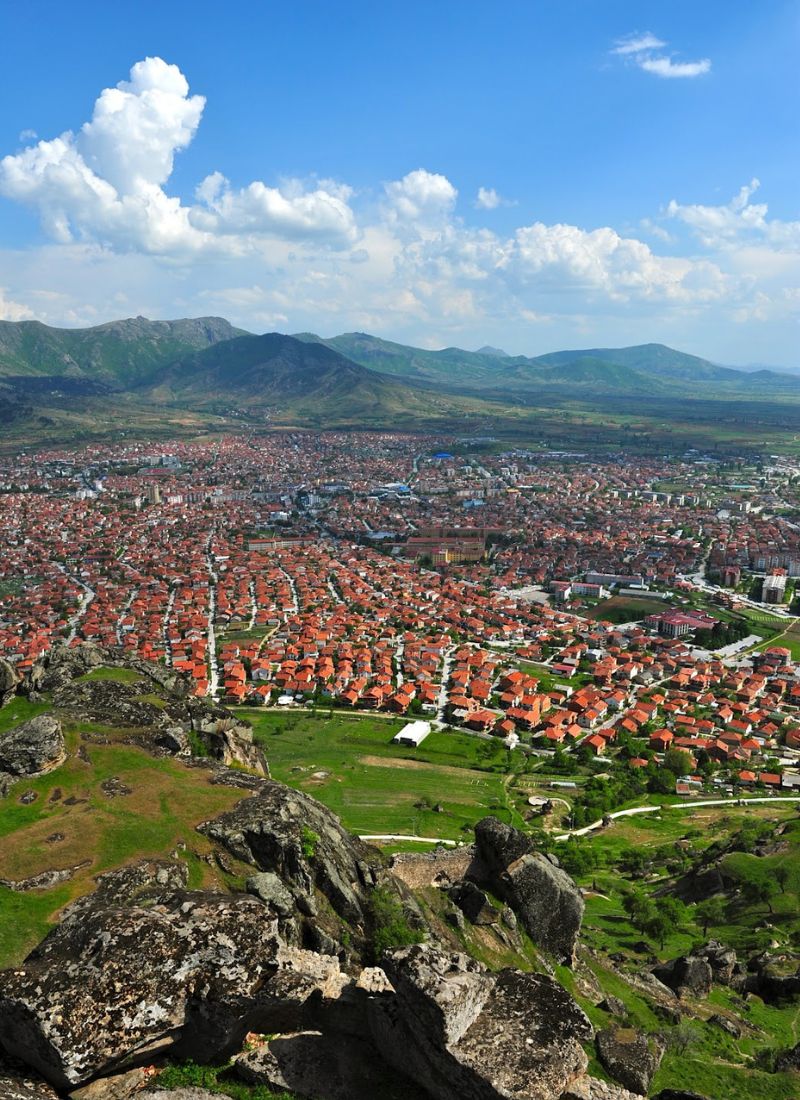 A view of Prilep from high above showing the houses with red roofs and the mountains and skyline in the background.