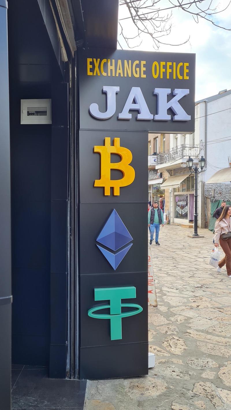 A physical crypto exchange office in the old bazaar of skopje, showing the logos for Bitcoin, Tether and Ethereum.