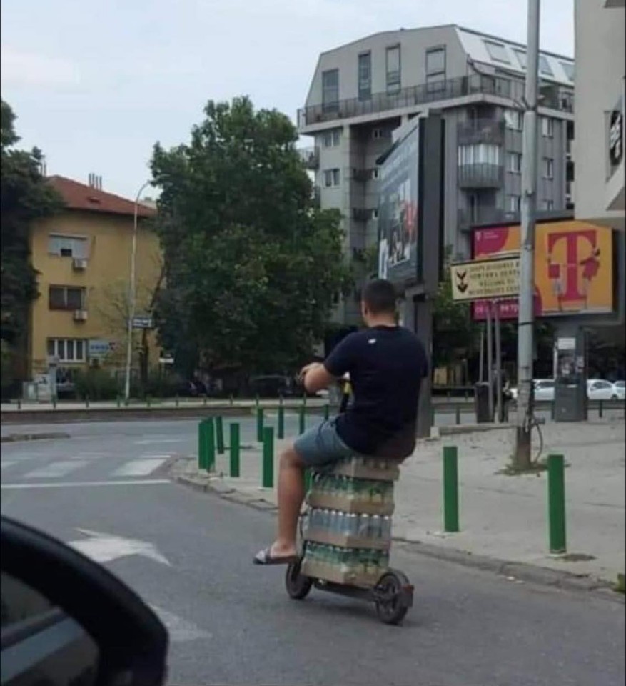 A man riding his scooter sitting on crates of beer in Skopje, Macedonia